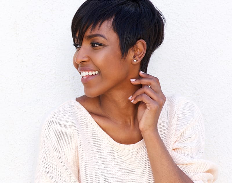 Woman smiling and looking off to the side, with her hand placed on her neck